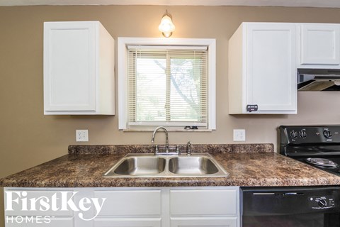 A kitchen with a granite countertop and a stove top oven.