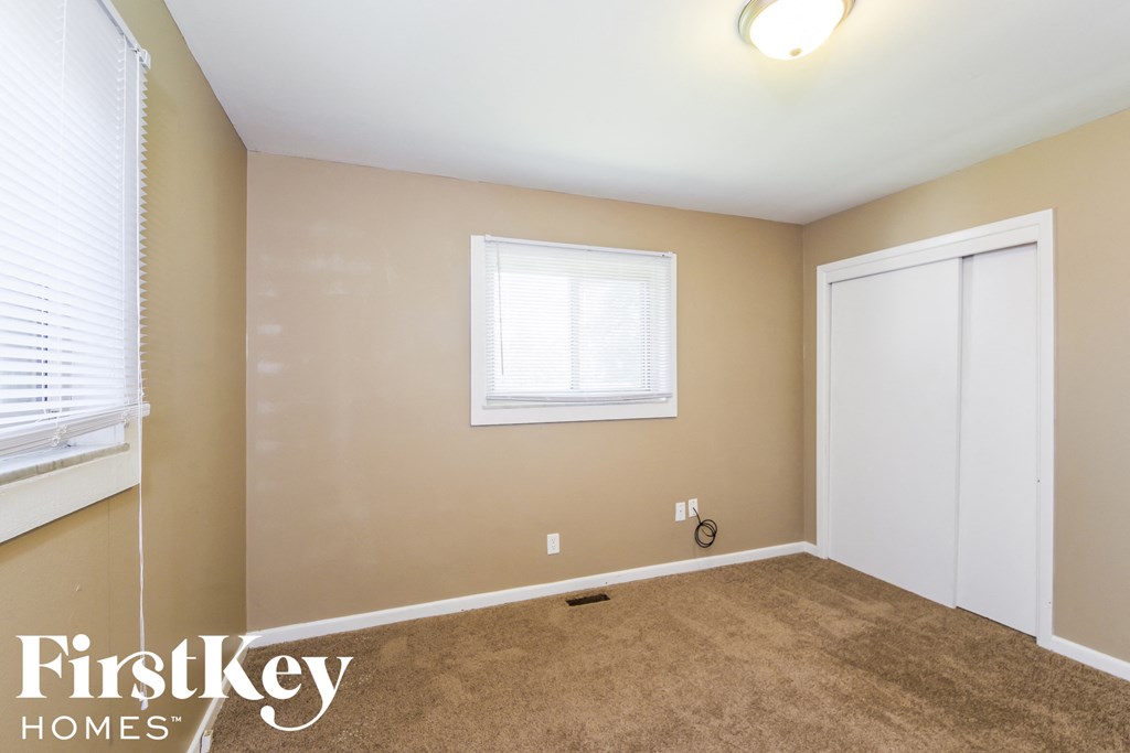 A room with a carpeted floor, a window, and a door.
