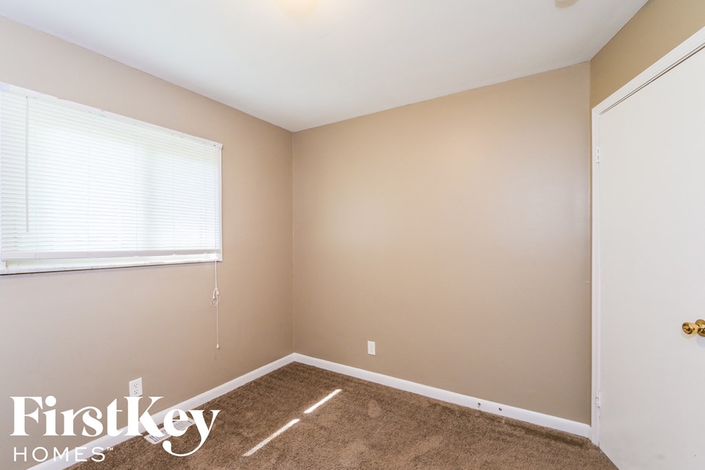 A room with a carpeted floor and a door on the right side.