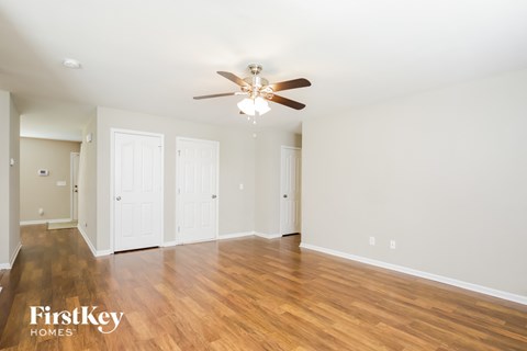 A spacious room with a ceiling fan and wooden flooring.