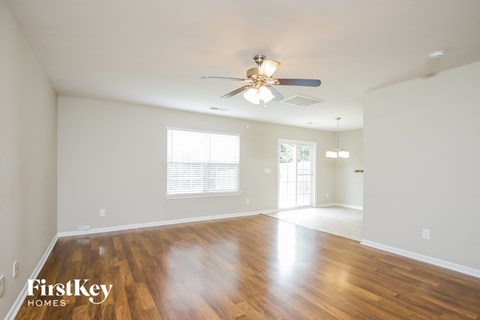 A spacious room with wooden floors and a ceiling fan.