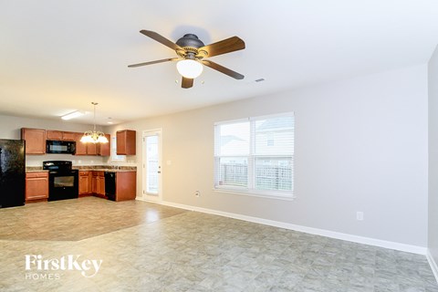 A spacious room with a ceiling fan and a kitchen area with appliances.