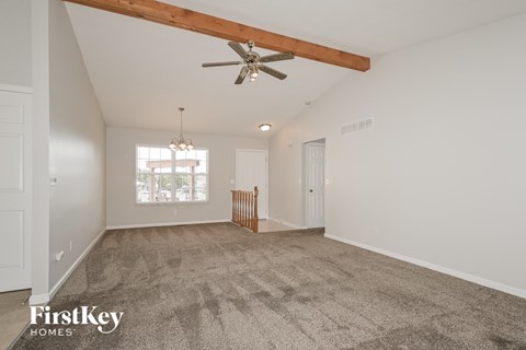 a spacious living room with carpet and a ceiling fan
