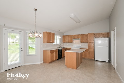a kitchen with wooden cabinets and white appliances and a door to the backyard