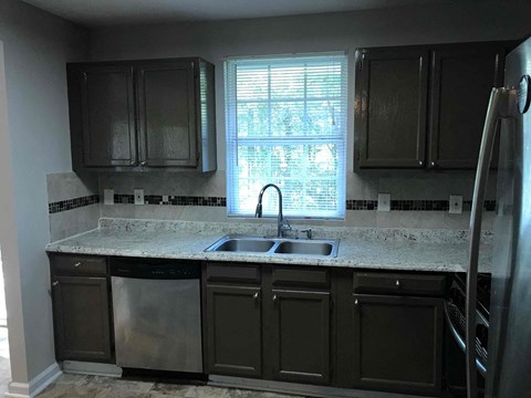 a kitchen with black cabinets and a sink and a window