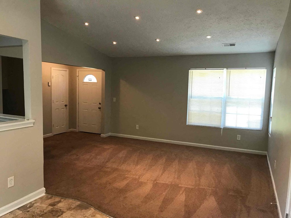 an empty living room with wood floors and a window