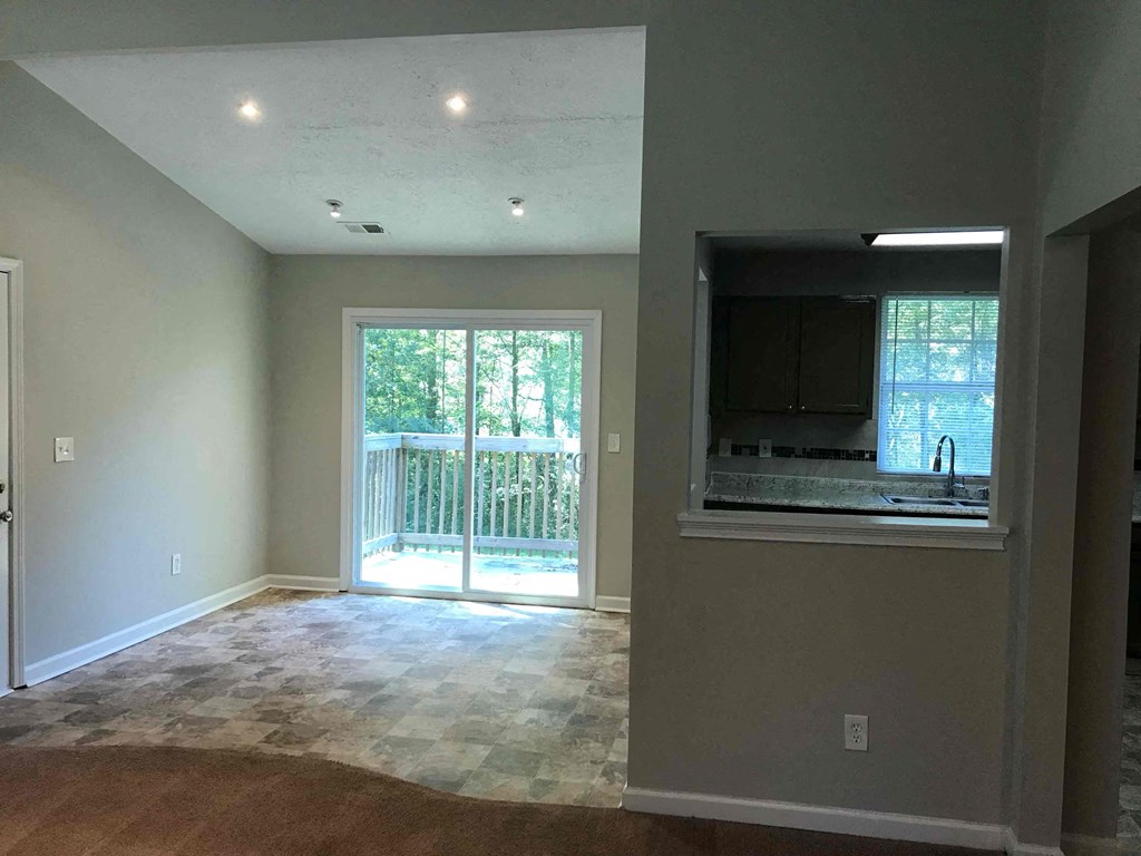 an empty living room with a tv and a sliding glass door