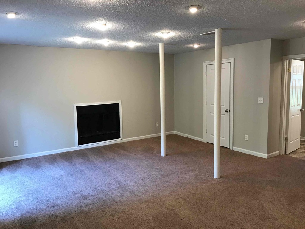 an empty living room with a fireplace and pillars