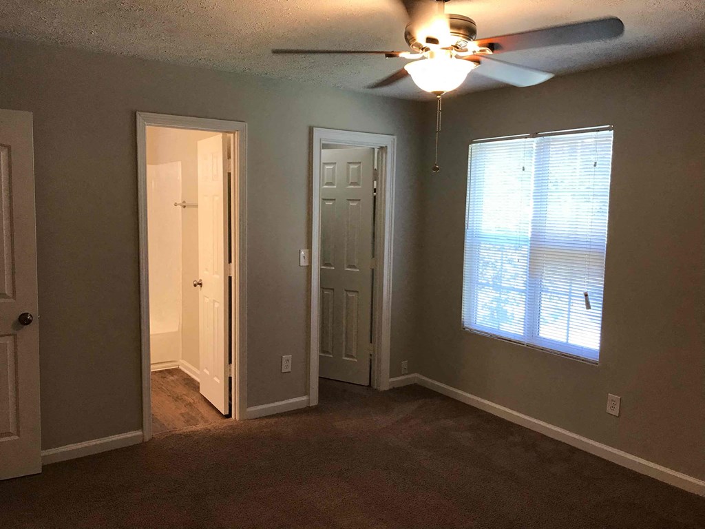 a living room with a ceiling fan and a door into a hallway