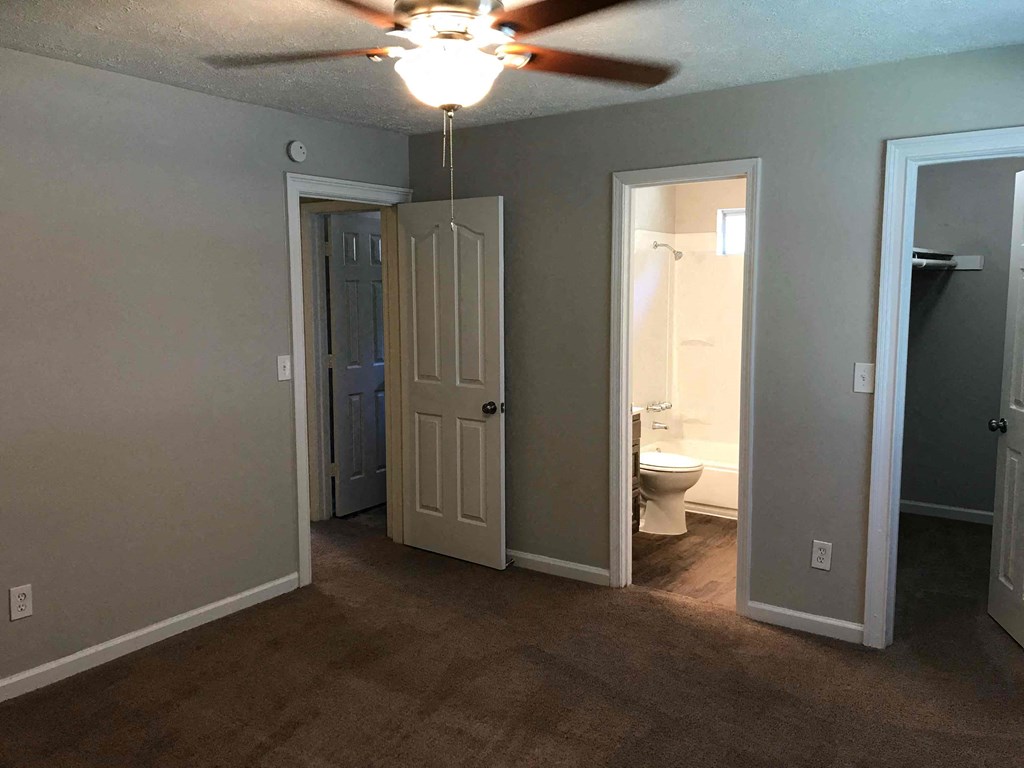 a living room with a ceiling fan and a door to a bathroom