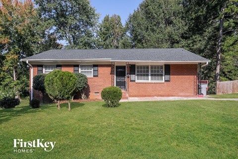 a small brick house with a lawn and trees