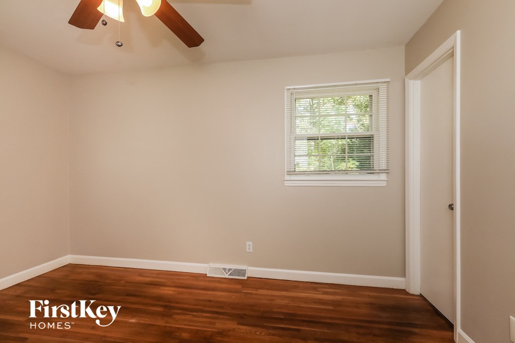 the bedroom has a hard wood floor and a ceiling fan