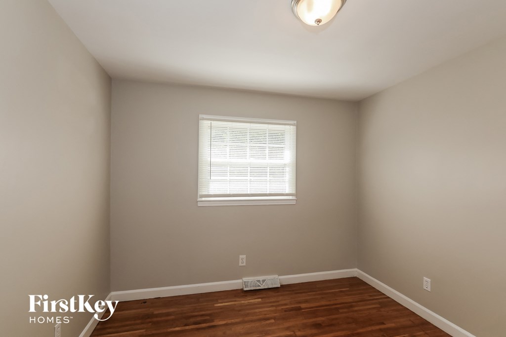 a bedroom with a wood floor and a window