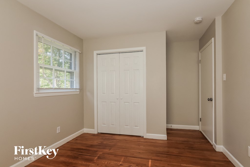 a bedroom with a closet and a white door and a window