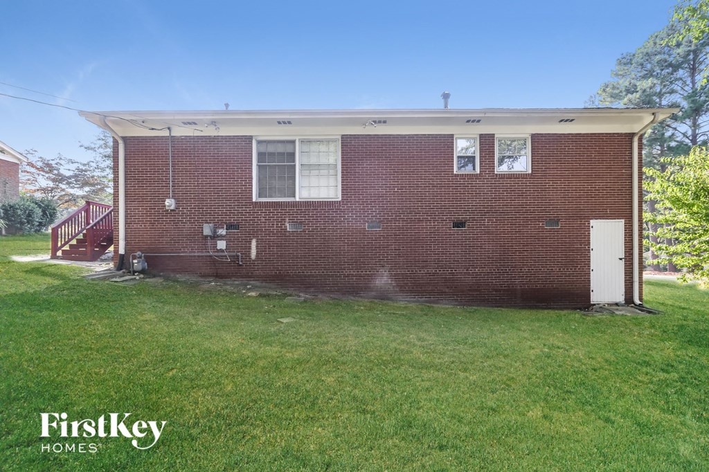 the front of a brick house with a lawn and a backdoor