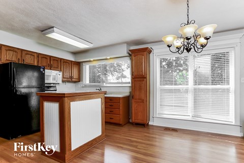 A kitchen with wooden cabinets and a black fridge.