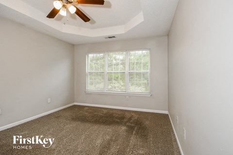 the living room of a home with carpet and a ceiling fan