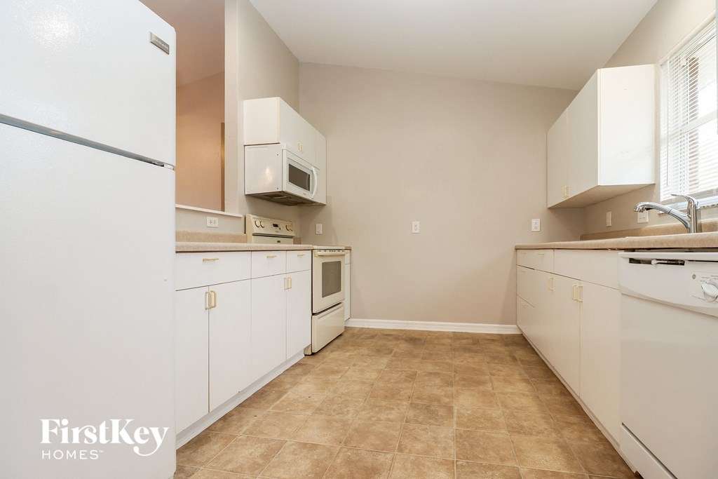 a kitchen with white cabinets and appliances and a window