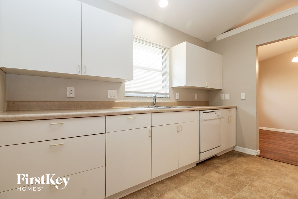 a kitchen with white cabinets and a sink and a window