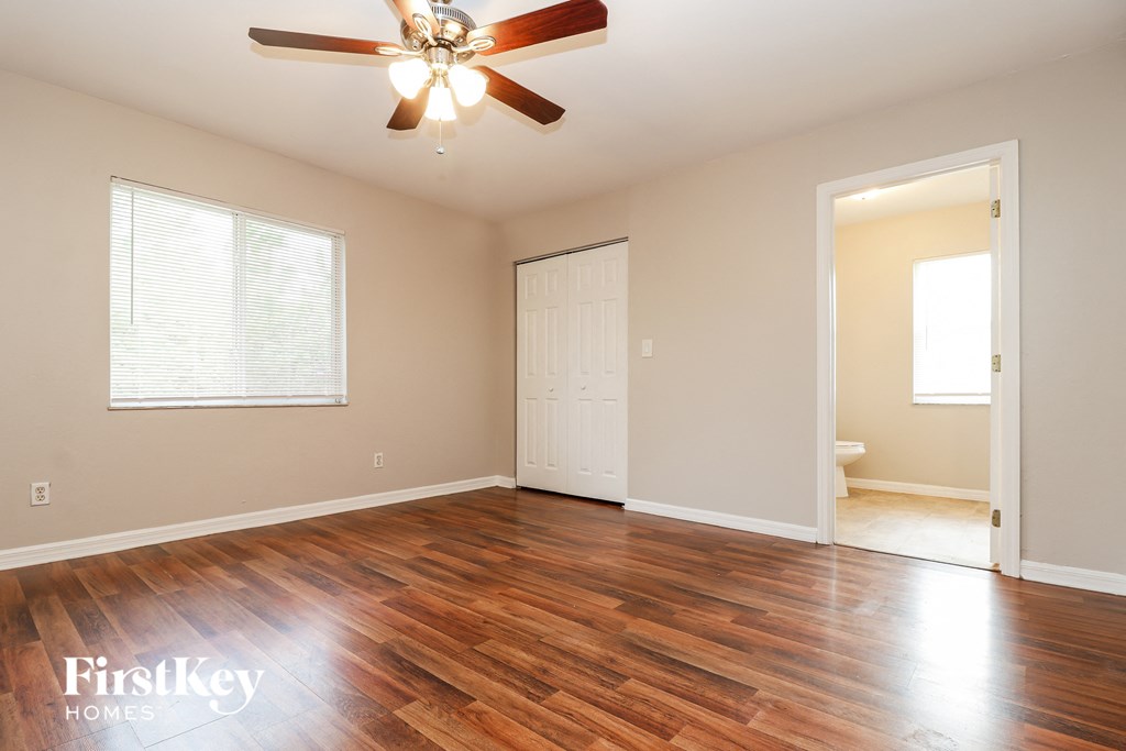 a clean and empty living room with wood floors and a ceiling fan