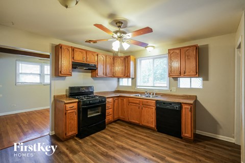 A kitchen with wooden cabinets and a black dishwasher.