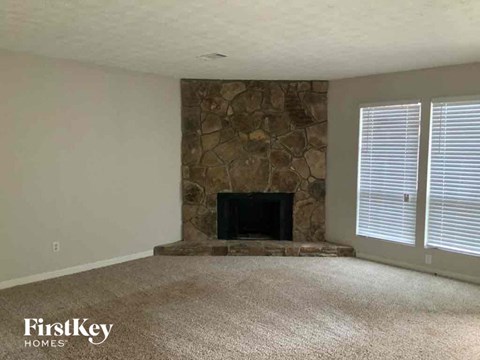 an empty living room with a stone fireplace