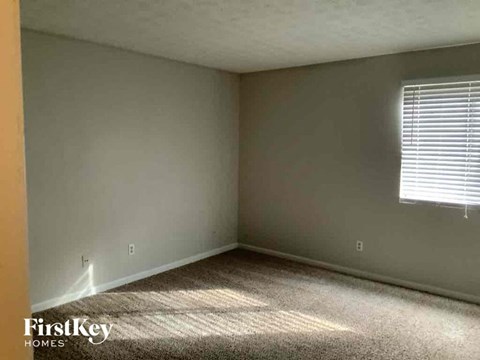 a bedroom with a window and a carpeted floor
