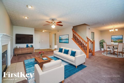 A living room with a white couch and a blue rug.