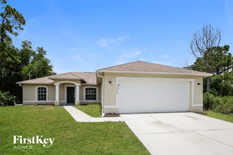 a beige house with a garage door and a lawn
