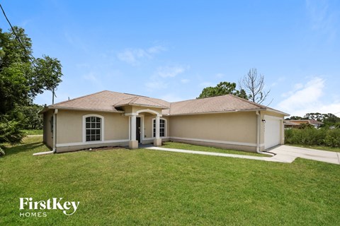 a beige house with a lawn and a driveway