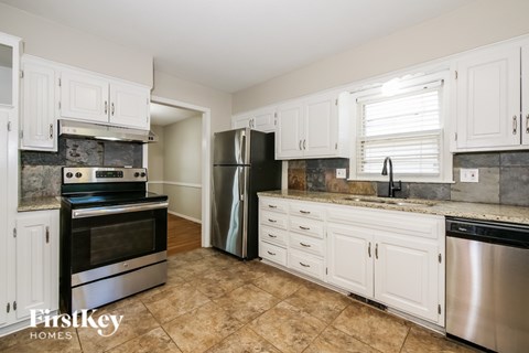 A kitchen with white cabinets and a tile floor.