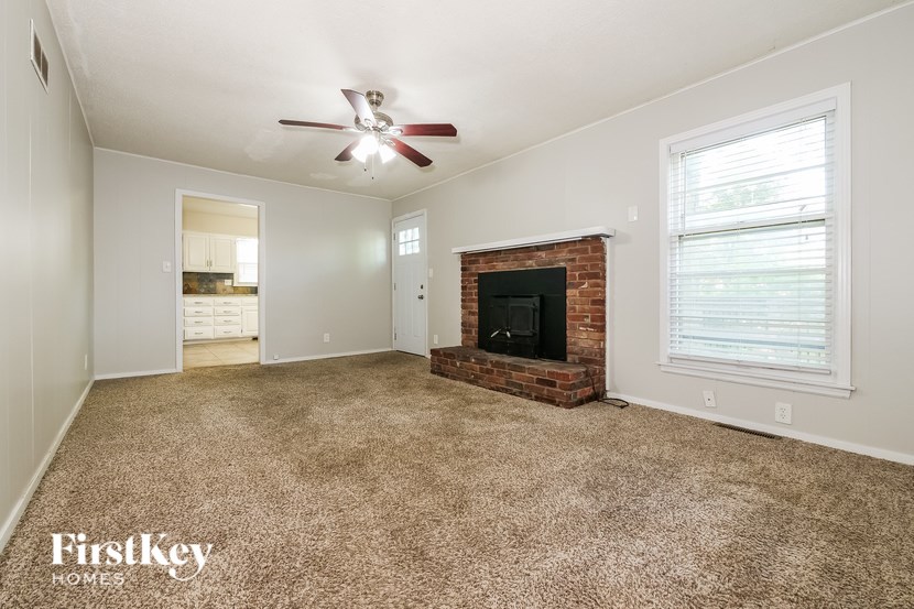 A living room with a fireplace and a ceiling fan.
