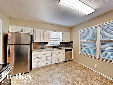 a kitchen with white cabinets and a stainless steel refrigerator
