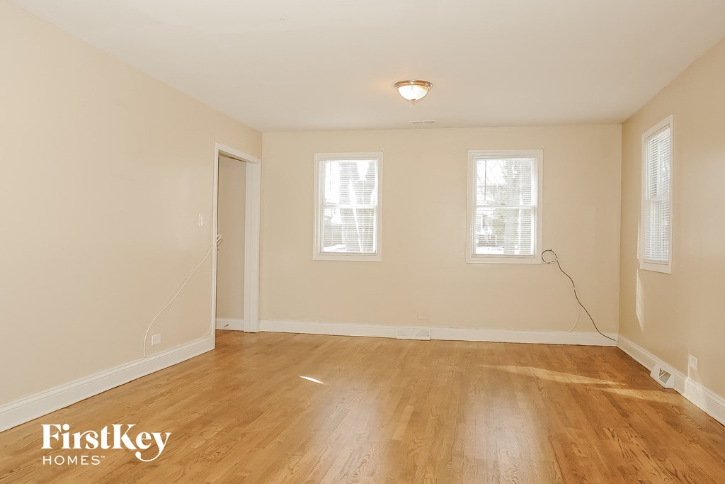 the living room of an empty house with wood flooring and two windows