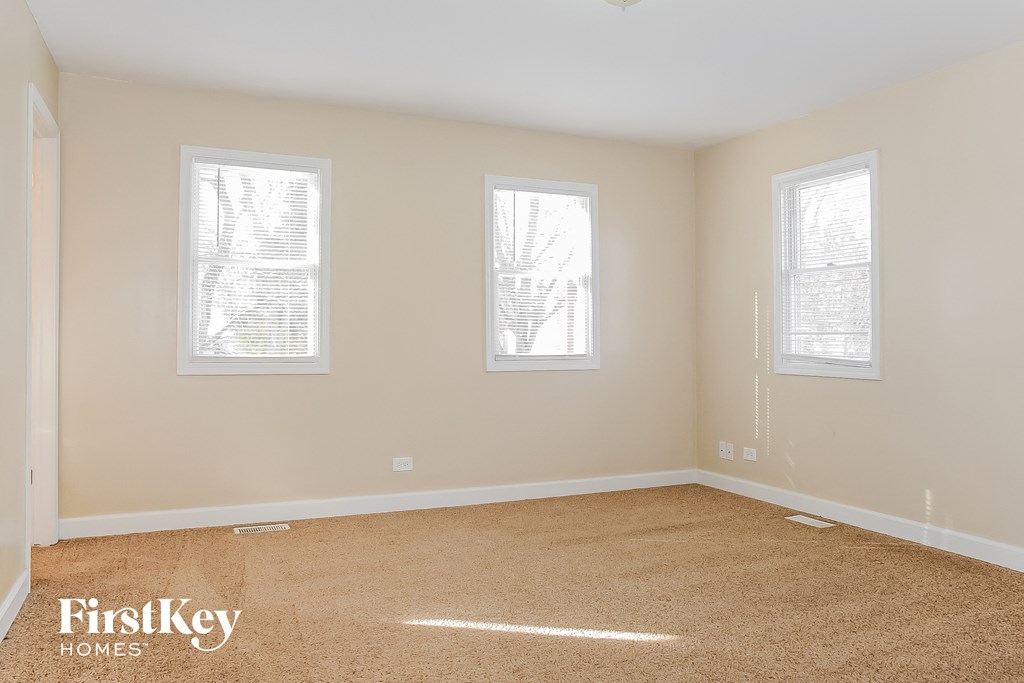 a bedroom with three windows and a carpeted floor