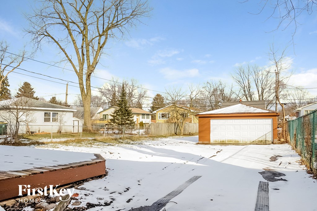 a backyard with a garage and a fence in the snow
