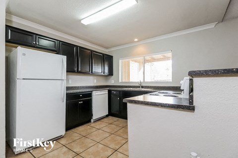 A kitchen with black cabinets and a white refrigerator.