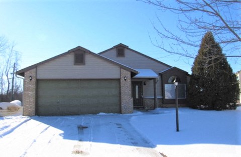 A house with a garage and a driveway covered in snow.