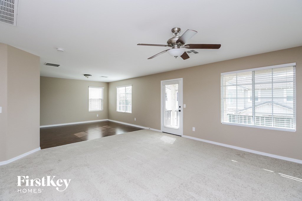 an empty living room with a ceiling fan and window