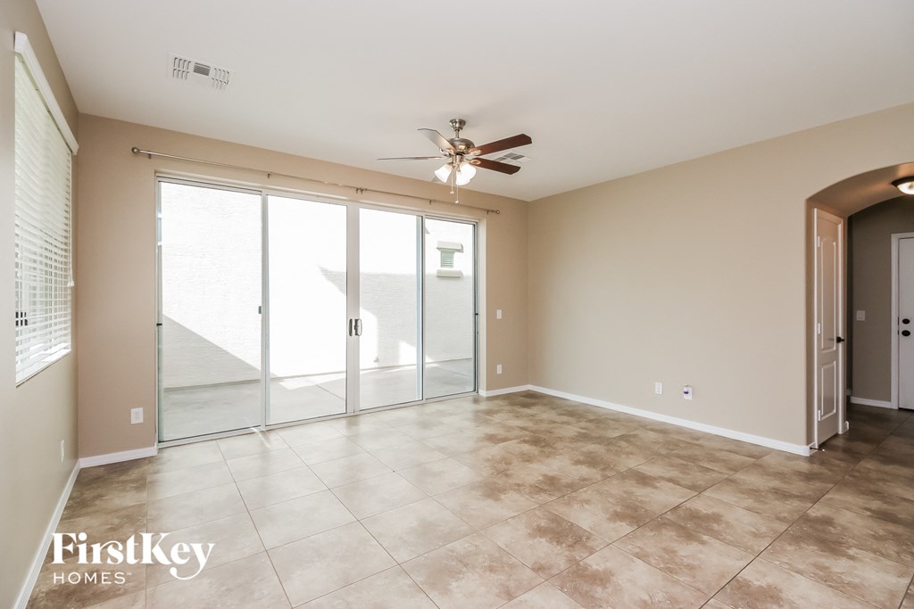 an empty living room with a ceiling fan and sliding glass doors
