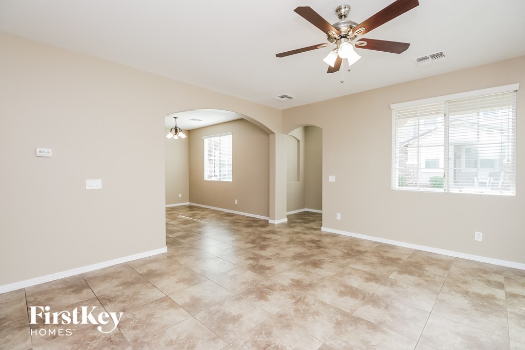 the spacious living room with a ceiling fan and tile flooring