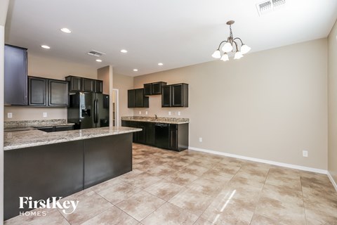 the kitchen is open to the living room and has granite counter tops and black appliances
