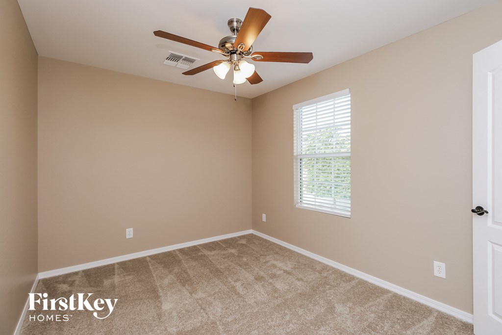 the bedroom has a ceiling fan and a carpeted floor