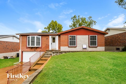 a small brick house with a porch and a lawn