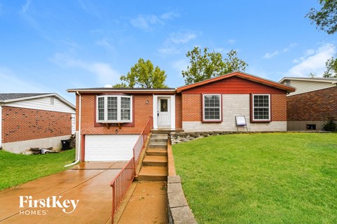 a red brick house with a white garage door and a green lawn