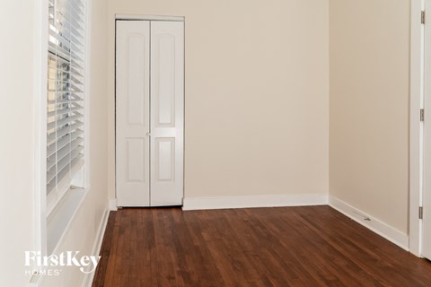 a bedroom with a door and wood floors and a window