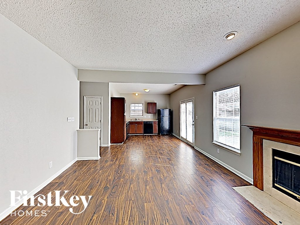 A spacious living room with wood flooring and a fireplace.