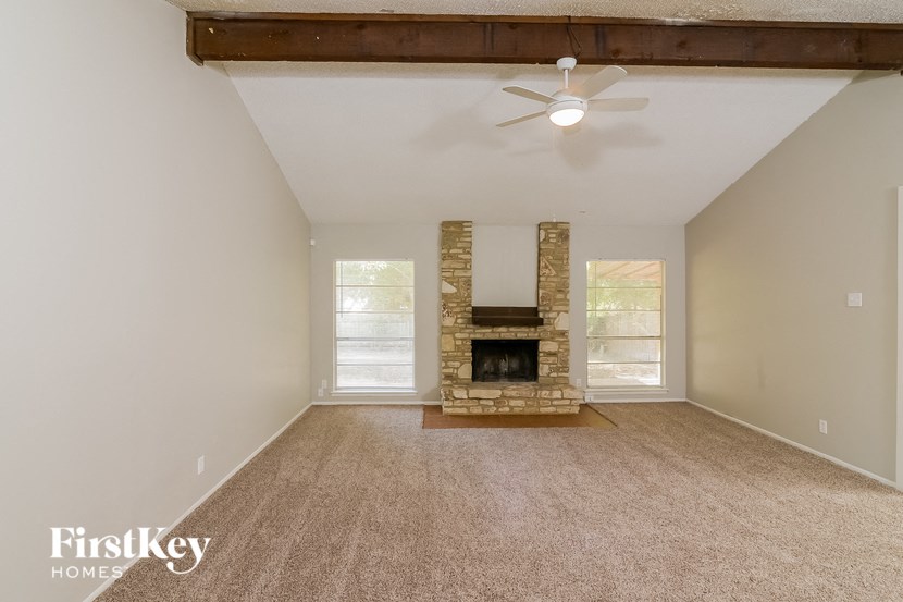an empty living room with a fireplace and a ceiling fan