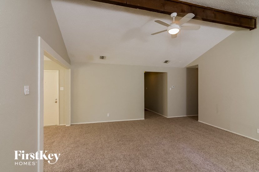 the living room of an empty house with a ceiling fan