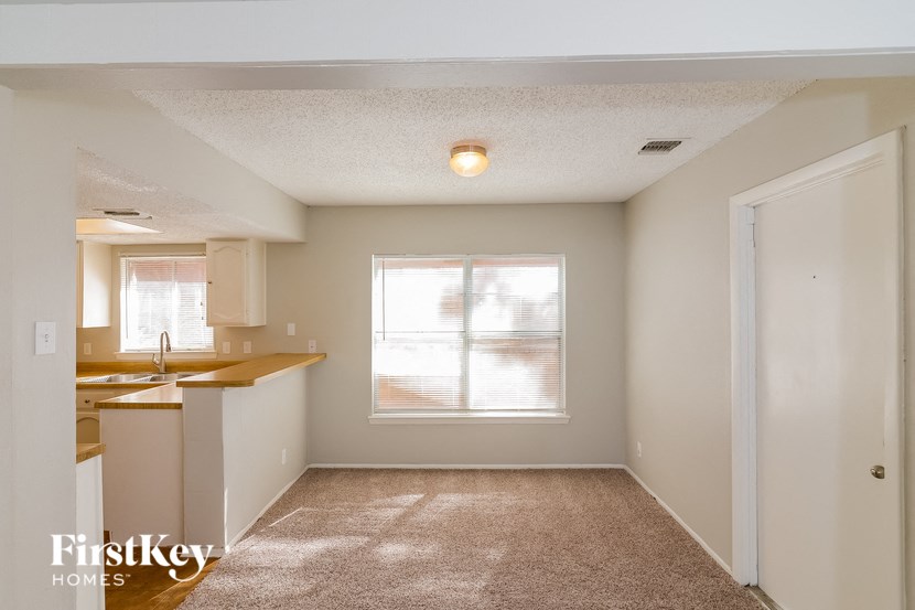 the kitchen and living room of an empty house with a window